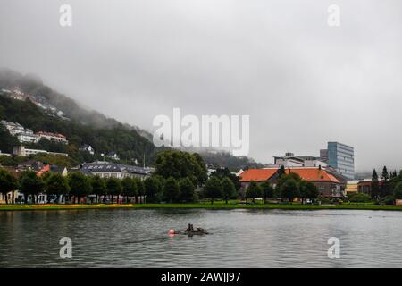 Éditorial 09.04.2019 Bergen Norvège vue du parc central avec lac dans la ville avec brouillard couvrant les maisons sur la colline de la montagne de Floyfjellet Banque D'Images