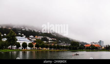 Éditorial 09.04.2019 Bergen Norvège vue du parc central avec lac dans la ville avec brouillard couvrant les maisons sur la colline de la montagne de Floyfjellet Banque D'Images