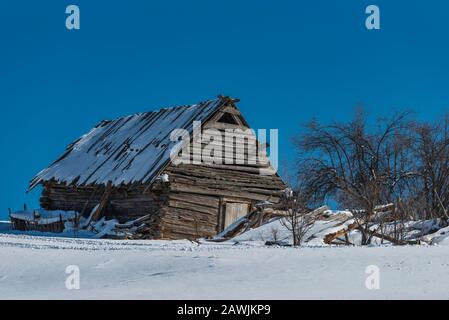 Ancienne grange en bois dans le champ, paysage de neige de montagne d'hiver Banque D'Images