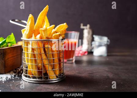 Les frites servent dans un panier métallique sur une table Banque D'Images