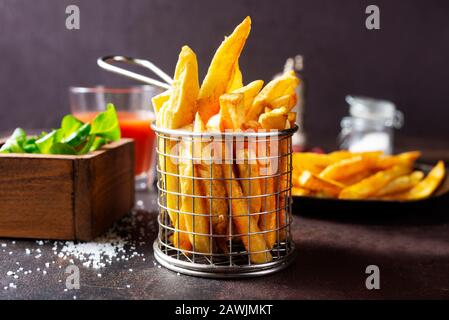 Les frites servent dans un panier métallique sur une table Banque D'Images