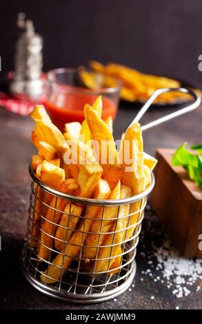 Les frites servent dans un panier métallique sur une table Banque D'Images