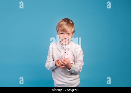 argent de poche pour enfants. Petit garçon avec une banque de porc Banque D'Images