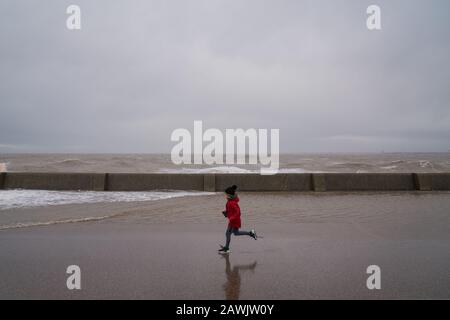 New Brighton, Wirral, Royaume-Uni. 9 février 2020. Un enfant longe la promenade alors que des vents et des vagues de force de gale se sont écrasés sur la promenade de New Brighton sur le Wirral dans le nord-ouest de l'Angleterre le dimanche 9 février 2020. Crédit: Christopher Middleton/Alay Live News Banque D'Images