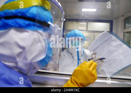 Une infirmière chinoise portant des vêtements de protection dans la zone d'isolement du nouveau coronavirus et de la pneumonie communique avec les autres par écrit à un hospice Banque D'Images