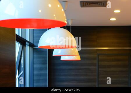 Les lampes blanches-orange modernes au plafond suspendu créent une atmosphère chaleureuse dans l'intérieur, un concept de décoration d'éclairage avec des abat-jour décoratifs Banque D'Images