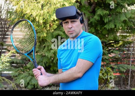 homme avec casque de réalité virtuelle et raquette de tennis avant un jeu et prêt à l'expérience de la simulation générée par ordinateur un jour d'été Banque D'Images