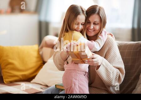 Portrait aux tons chauds de la jolie fille embrassant maman après avoir donné cadeau pour anniversaire ou Fête Des Mères, espace de copie Banque D'Images