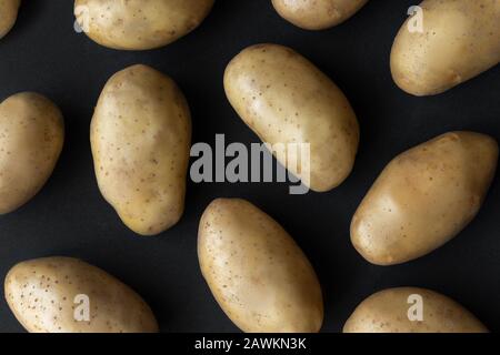 Saupoudrez les pommes de terre biologiques brutes sur fond sombre Banque D'Images