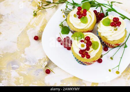 Doux cupcake festif avec crème et baies аnd une bougie un fond clair Banque D'Images