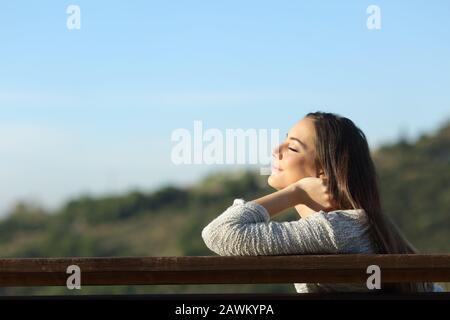 Profil d'une femme détendue assise sur un banc respirent l'air frais dans la montagne une journée ensoleillée Banque D'Images