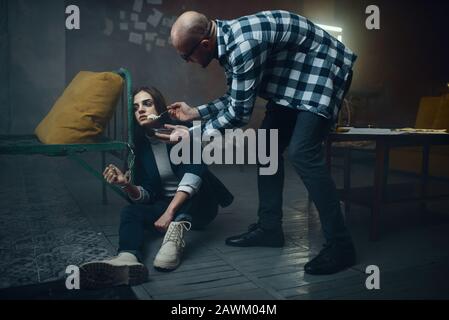 L'kidnappeur maniaque alimente sa victime menottée Banque D'Images