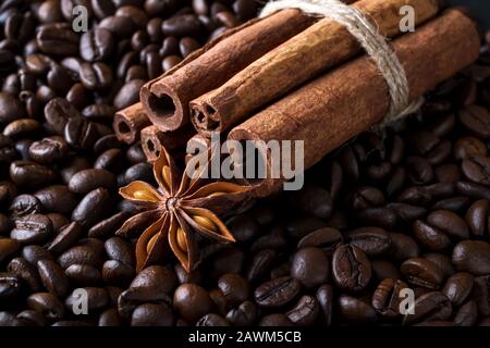 Bâtonnets d'anis et de cannelle sur fond de grains de café rôtis. Image clé des ingrédients des boissons à base de café. Gros plan. Banque D'Images