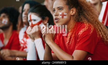 Les fans de football de sexe féminin qui regardaient le match au stade sont inquiets. Groupe de supporters de l'équipe de football anglaise qui regardent le match de près des stands Banque D'Images