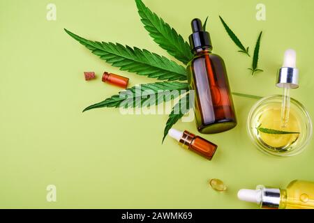 Bouteilles de verre avec CBD, huile de chanvre, teinture de THC et feuilles de chanvre sur fond jaune Banque D'Images