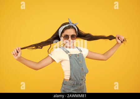 Cheveux forts. Cute kid fashion girl. @Summer mode concept. Fille de long cheveux bouclés attachés lunettes de foulard. Tendance de la mode. Vous pouvez avoir tout ce que vous voulez si robe pour elle. Peu de fashionista. Banque D'Images