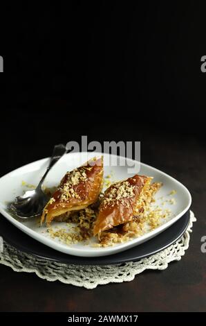 Concept de sucré turc. Triangles baklava, dessert turc traditionnel sucré avec pâte phyllo, noix et miel. Fond sombre. Banque D'Images