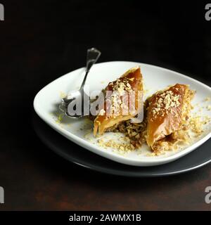 Concept de sucré turc. Triangles baklava, dessert turc traditionnel sucré avec pâte phyllo, noix et miel. Fond sombre. Banque D'Images