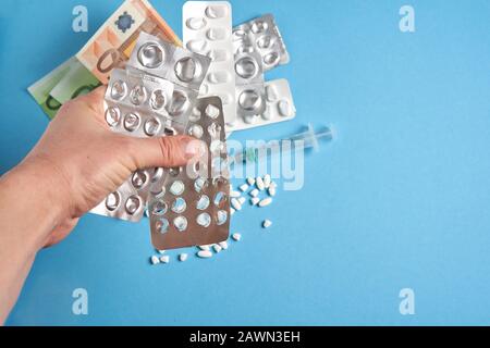 Pilules vides blisters pour les médicaments seringue individuelle et l'argent se trouvent sur un fond bleu Coûteux médicament assurance santé concept. Traitement coûteux Banque D'Images