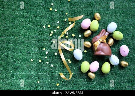 Œufs de Pâques dorés et lapin au chocolat avec espace de copie pour le texte sur fond vert Banque D'Images