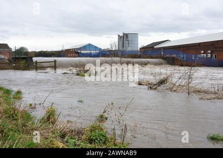 Storm ciara, River irwell éclate ses banques avec des bâtiments industriels en arrière-plan à radcliffe bury lancashire royaume-uni Banque D'Images