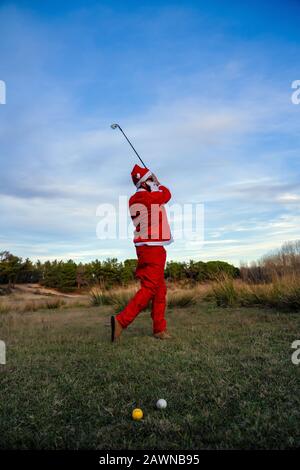 Le Père Noël jouant au golf pendant la journée Banque D'Images