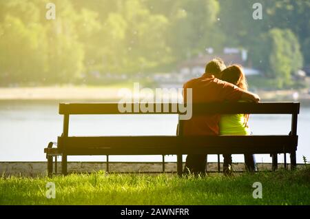 Vue arrière d'un jeune couple assis sur un banc de parc. Silhouette romantique de personnes dans l'amour. Banque D'Images