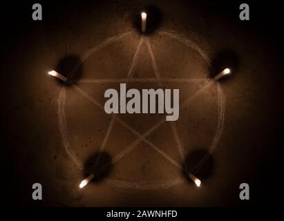 Symbole de pentagramme blanc sur sol en béton. Illuminé de bougies. Arrière-plan sombre. Occultisme effrayant et mystique Banque D'Images