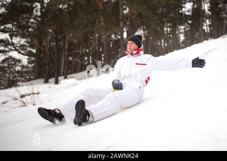 Une femme adulte se déplace sur la glace de traîneau à partir d'une montagne escarpée. Plaisir en hiver. Banque D'Images