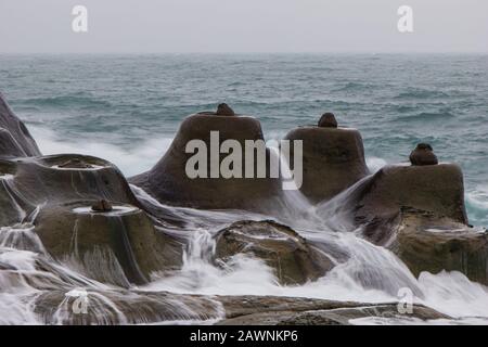 L'eau qui coule entre les rochers en forme de bougie (bougies de mer) au Geopark de Yehliu (Yehliu) à Taiwan en gris. Banque D'Images