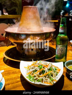 Un hotpot mongol est servi à table au restaurant avec de la bière locale Tsingtao, le quartier Xi Cheng Hutong, Pékin, Chine, Asie Banque D'Images