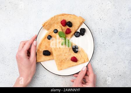 Crêpes Françaises Ou Thin Pancakes Ou Russe Ukrainien Blini Avec Berries D'Été Sur Plaque. Assiette De Pancakes Pour Les Mains De La Femme. Vue Du Plan D'Examen Banque D'Images