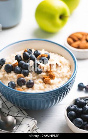 Gruau Bol À Porridge Avec Noix Et Bleuets Sur La Table Blanche. Concept De Petit Déjeuner Sain, Orientation Verticale Banque D'Images