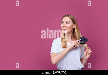 belle femme souriante se brossant les cheveux avec un sabot Banque D'Images