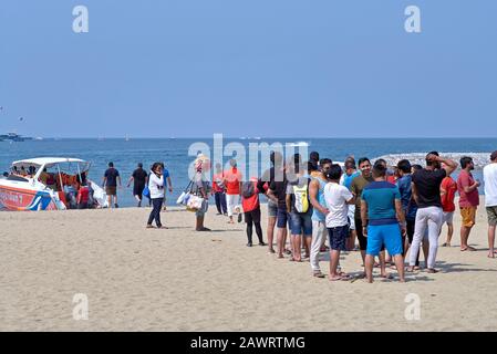 Touristes asiatiques indiens faisant la queue sur la plage pour un voyage en bateau au départ de Pattaya Thaïlande tourisme Asie du Sud-est Banque D'Images