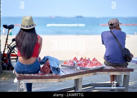 Homme et femme assis sur un banc avec vue sur la mer, surplombant l'océan à Pattaya Beach, Thaïlande, Asie du Sud-est Banque D'Images