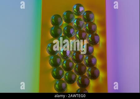 Billes de verre colorées sur fond jaune et rose Banque D'Images