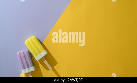 Vue de dessus de deux boutons-pression colorés , concept créatif minimal d'été sur fond plat mauve et jaune avec espace de copie Banque D'Images