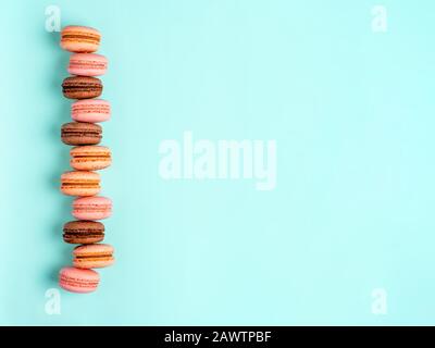 Macarons avec espace de copie. Rangée de macarons ou macarons français parfaits sur fond bleu. Vue de dessus ou plat Banque D'Images