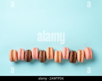 Macarons avec espace de copie. Rangée de macarons ou macarons français parfaits sur fond bleu. Vue de dessus ou plat Banque D'Images