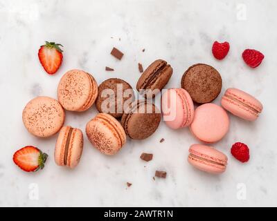 Composition avec macarons français sur fond de marbre blanc. Vue sur le dessus des macarons pastel colorés ou du macaron avec baies et chocolat Banque D'Images