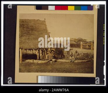 Quatre hommes Ainu avec deux bateaux, par toit de chaume, sur l'île de Hokkiado, Japon Banque D'Images