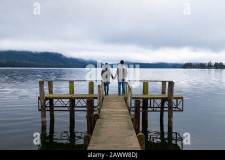 Un jeune couple asiatique tenant les mains sur le pont Lac te Anau Nouvelle-Zélande Banque D'Images