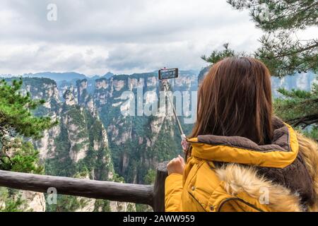 Une jeune fille touristique asiatique prend une photo à l'aide d'un smartphone au parc forestier national de Zhangjiajie, site classé au patrimoine mondial de l'UNESCO, Wulingyuan, Hunan, Chine Banque D'Images