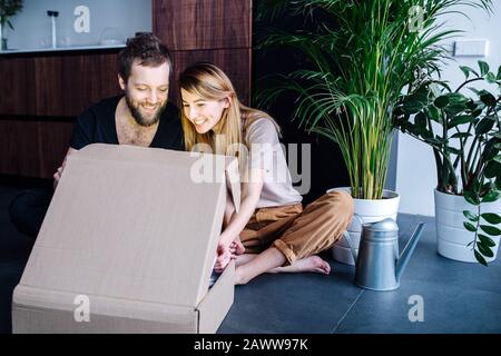 Heureux couple regardant à l'intérieur d'une boîte, brillant de l'intérieur Banque D'Images