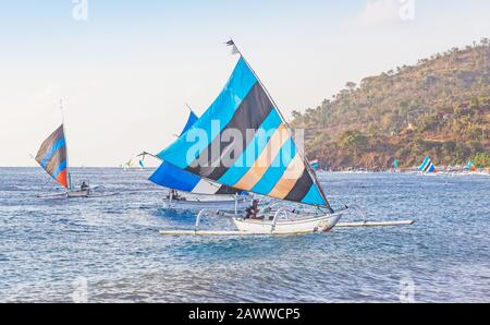 Les pêcheurs des jukungs de voile traditionnels (canoës à l'outrigger) retournaient avec leur prise à Ahmed Beach. Banque D'Images