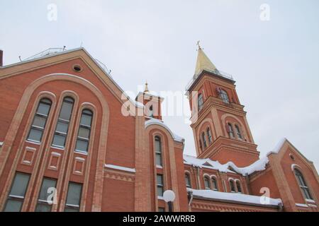 Fragment d'une église en brique rouge avec fenêtres et toit doré. Banque D'Images