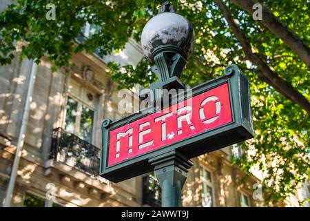 Magnifique panneau de métro rouge typique (Paris, France). Style européen, prise de vue à angle bas avec un arrière-plan flou. Elément de rue en acier vert Banque D'Images