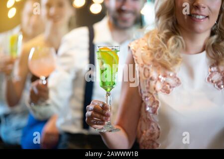 Les gens qui tiennent des cocktails colorés dans un bar Banque D'Images