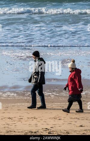 Les gens qui apprécient de marcher le long de la rive à Fistral Beach en fin d'après-midi, à Newquay, en Cornwall. Banque D'Images